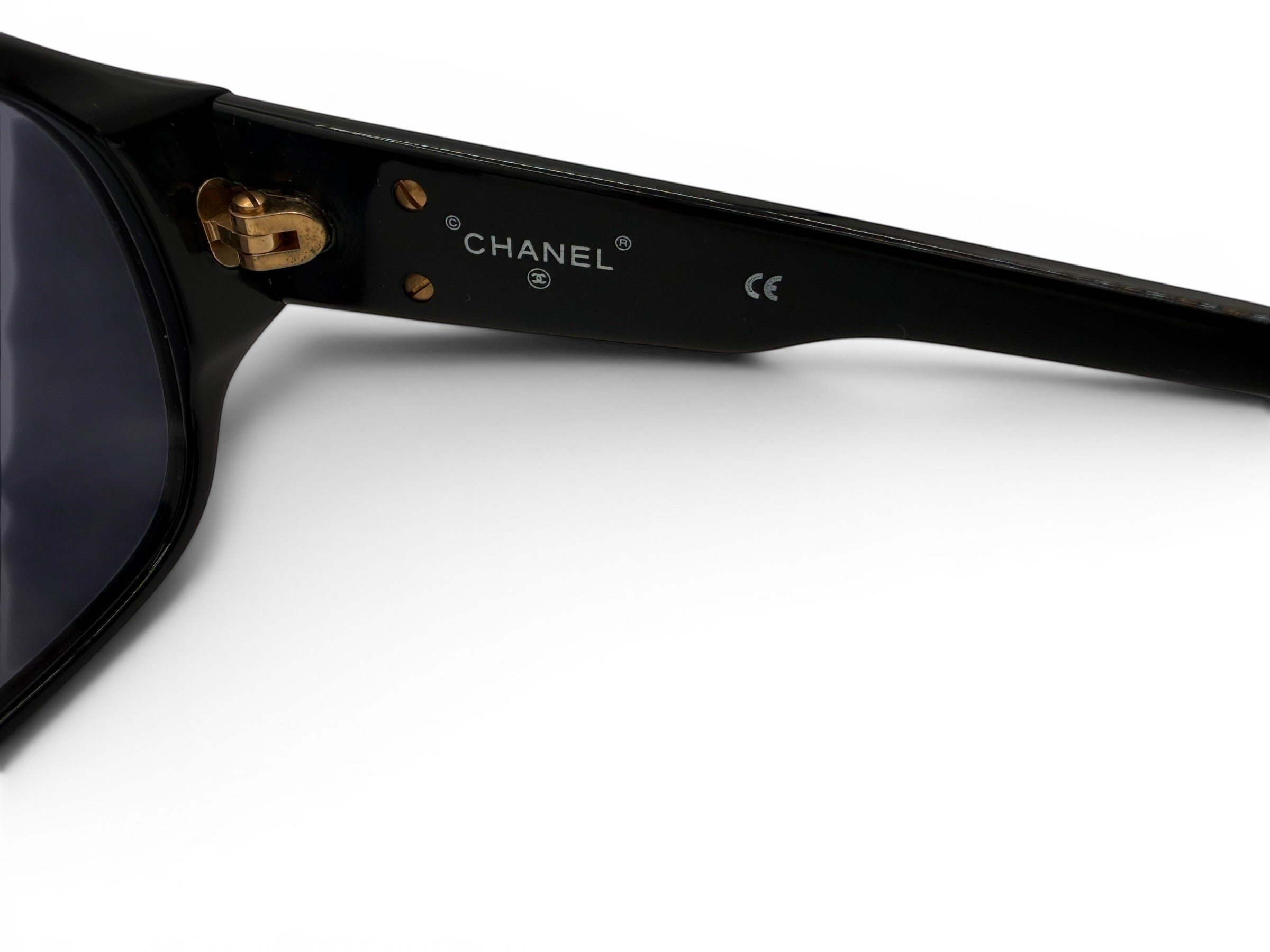 Curated Closet vintage black acetate Chanel sunglasses with gold CC logos and dark lenses.